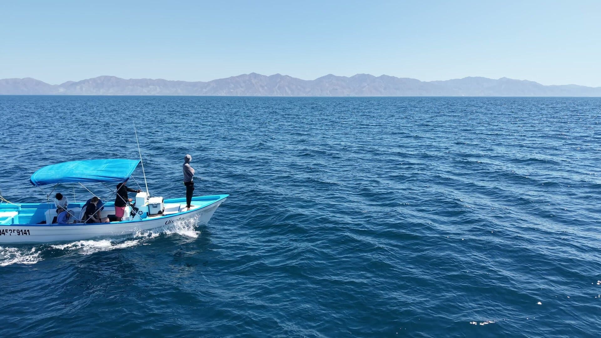 A passenger panga crossing open water with mountains on the horizon