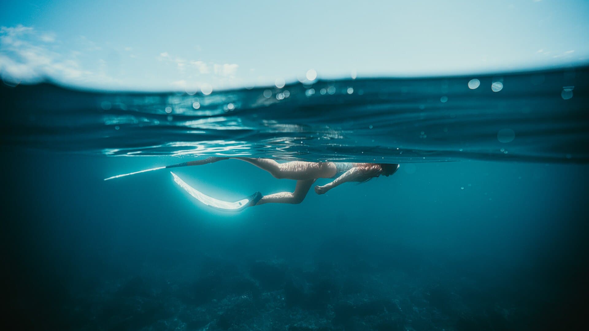 A snorkeler swimming just below the open-water surface