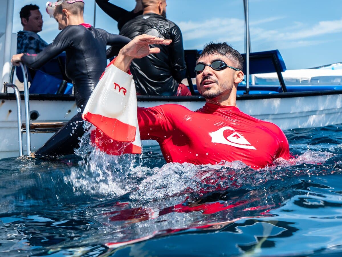 A snorkeler beside a panga while other guests prepare on board