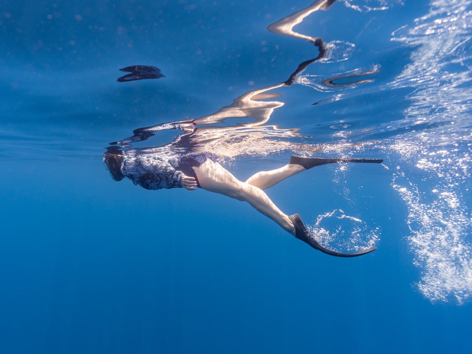 A snorkeler swimming near the surface with bubbles trailing behind