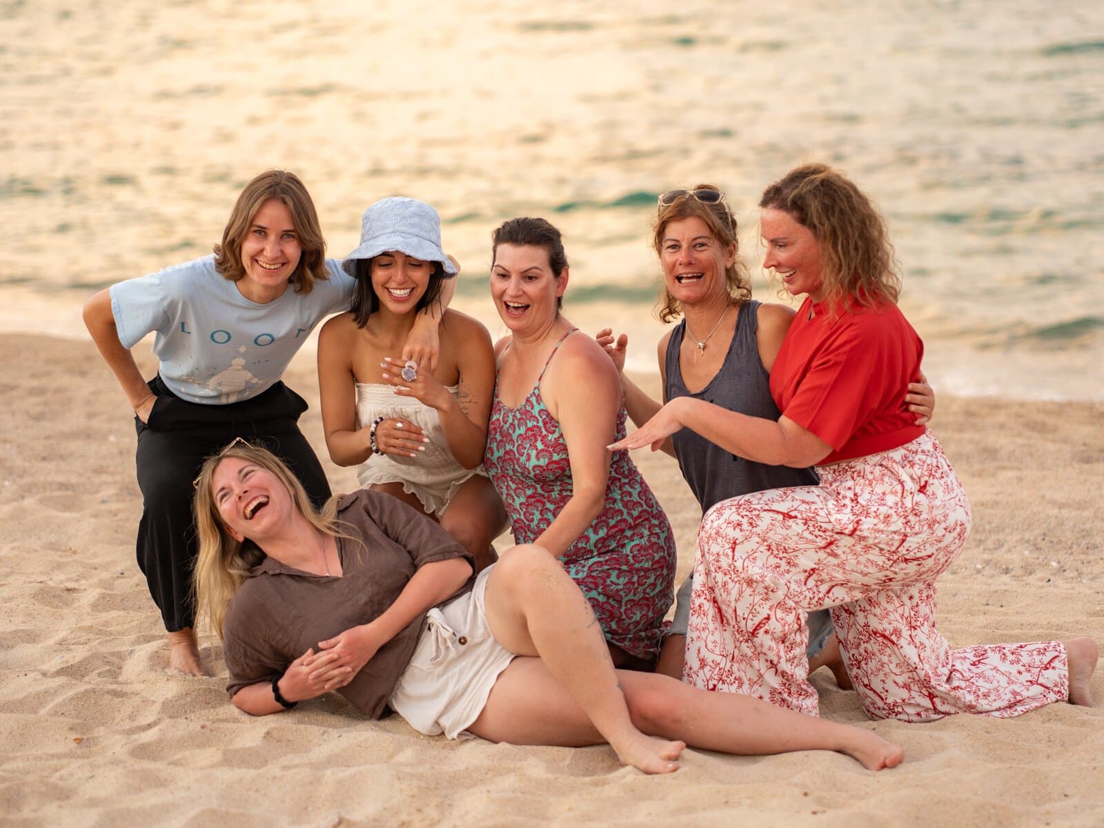 Six people laughing together on a beach