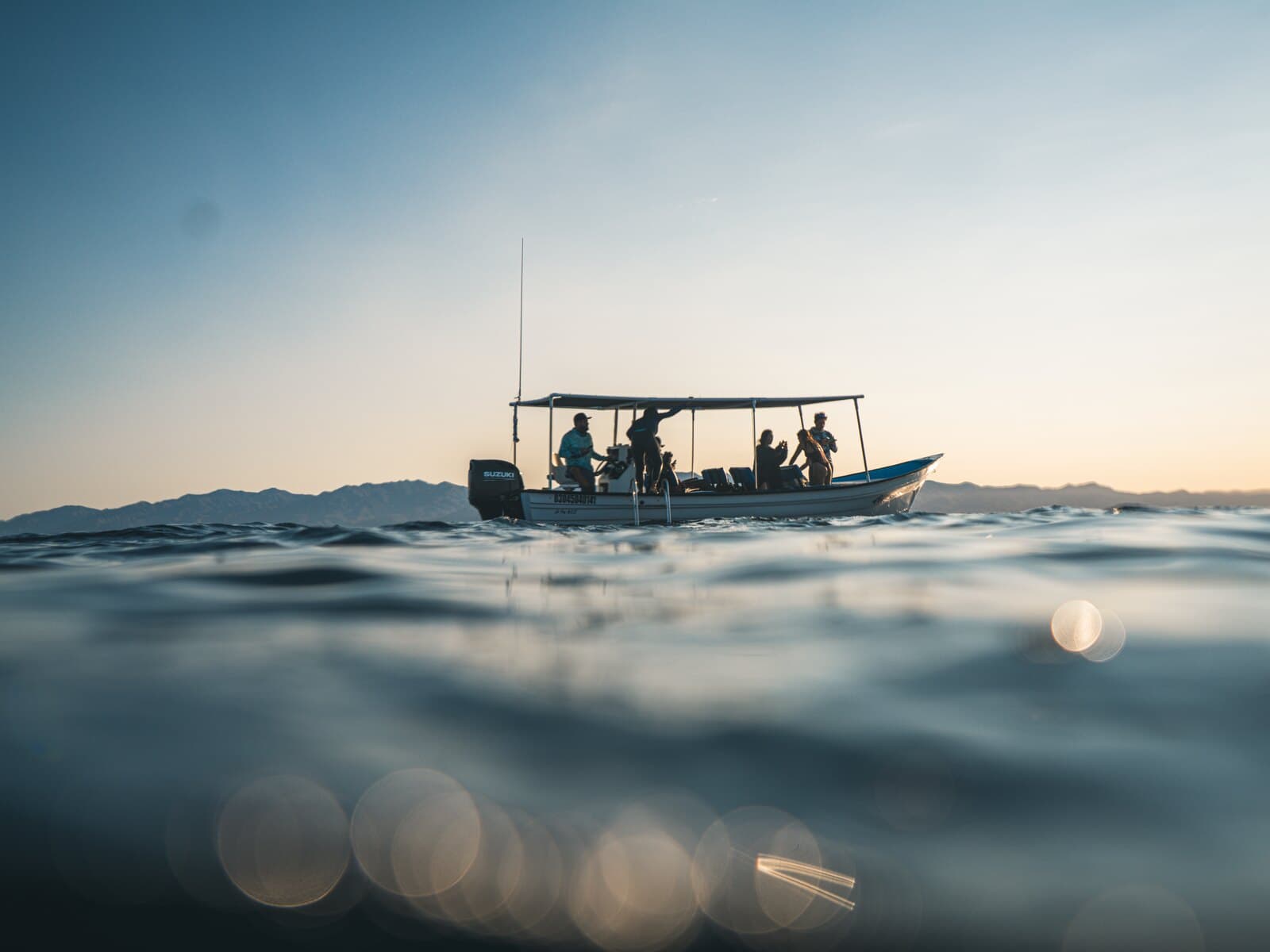 A passenger panga crossing open water near sunset