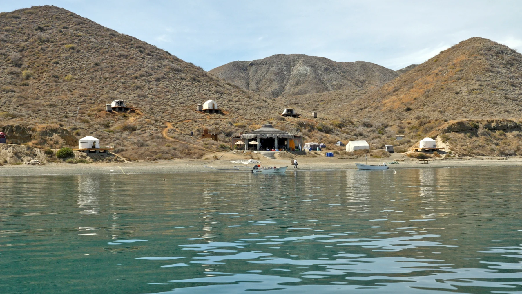 A remote camp spread along a protected cove beneath arid hills