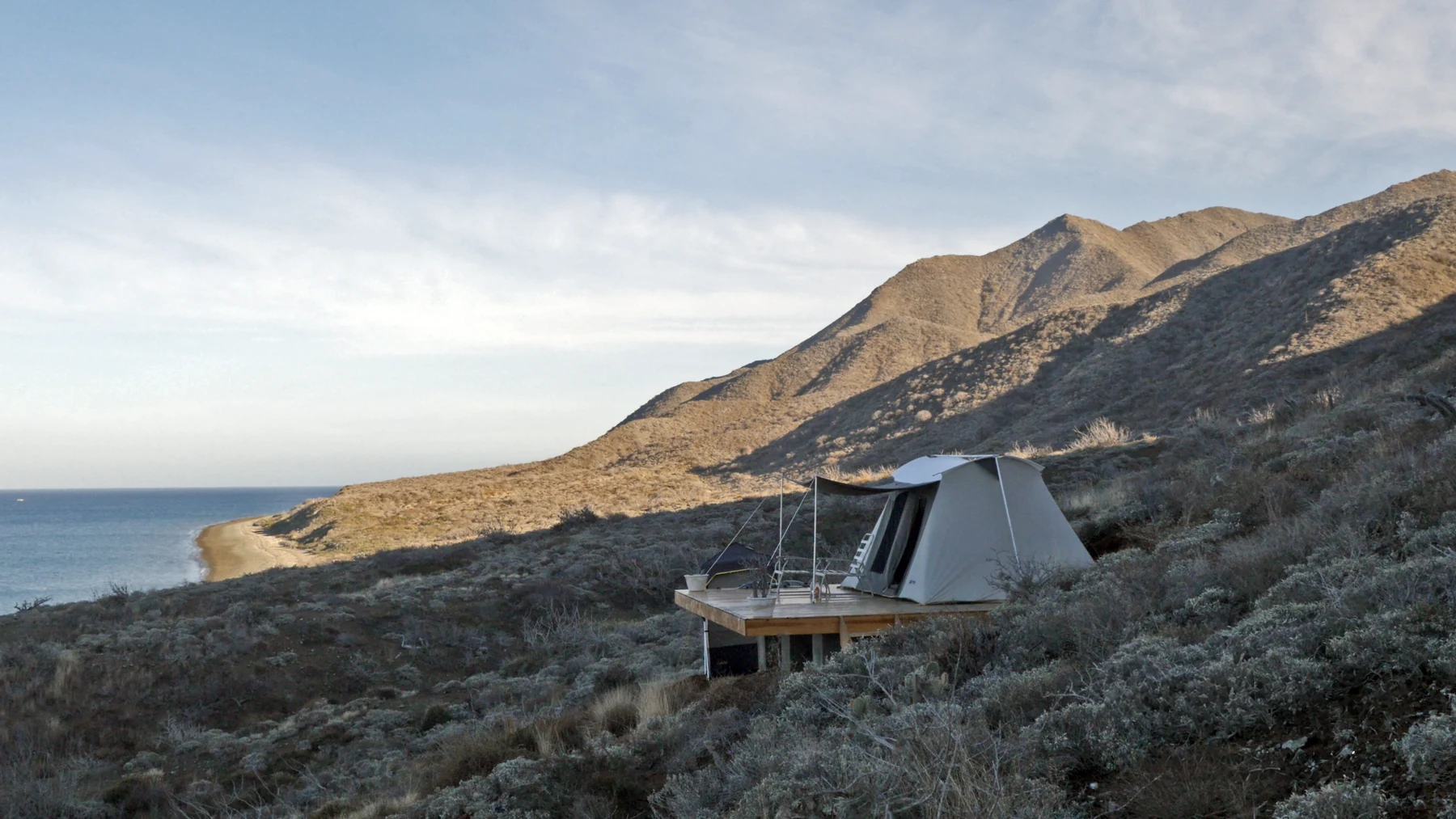 A canvas guest tent on a hillside above the bay
